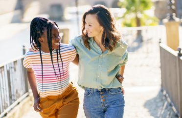 Two friends talking together on the street. Multiethnic women